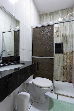 A bathroom with a black marble sink, white toilet, and a shower area with patterned tiles. - Pousada Salomé (Bonito)