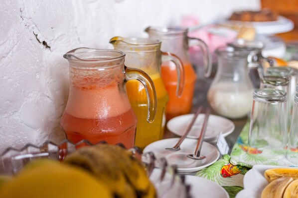 A table with various beverages in pitchers and glasses, surrounded by plates and utensils.