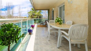 Een balkon met een tafel en stoelen, planten in potten en uitzicht op de stad.