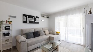Een moderne woonkamer met een beige bank, een glazen salontafel en een witte tv-meubel.