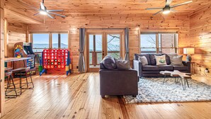 A wooden cabin interior with a sofa, a table, and a ceiling fan.