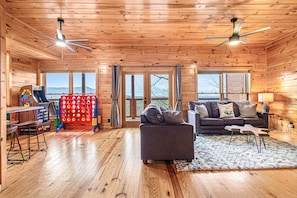 Ein Interieur einer Holzhütte mit einer Couch, einem Tisch und einem Deckenventilator.