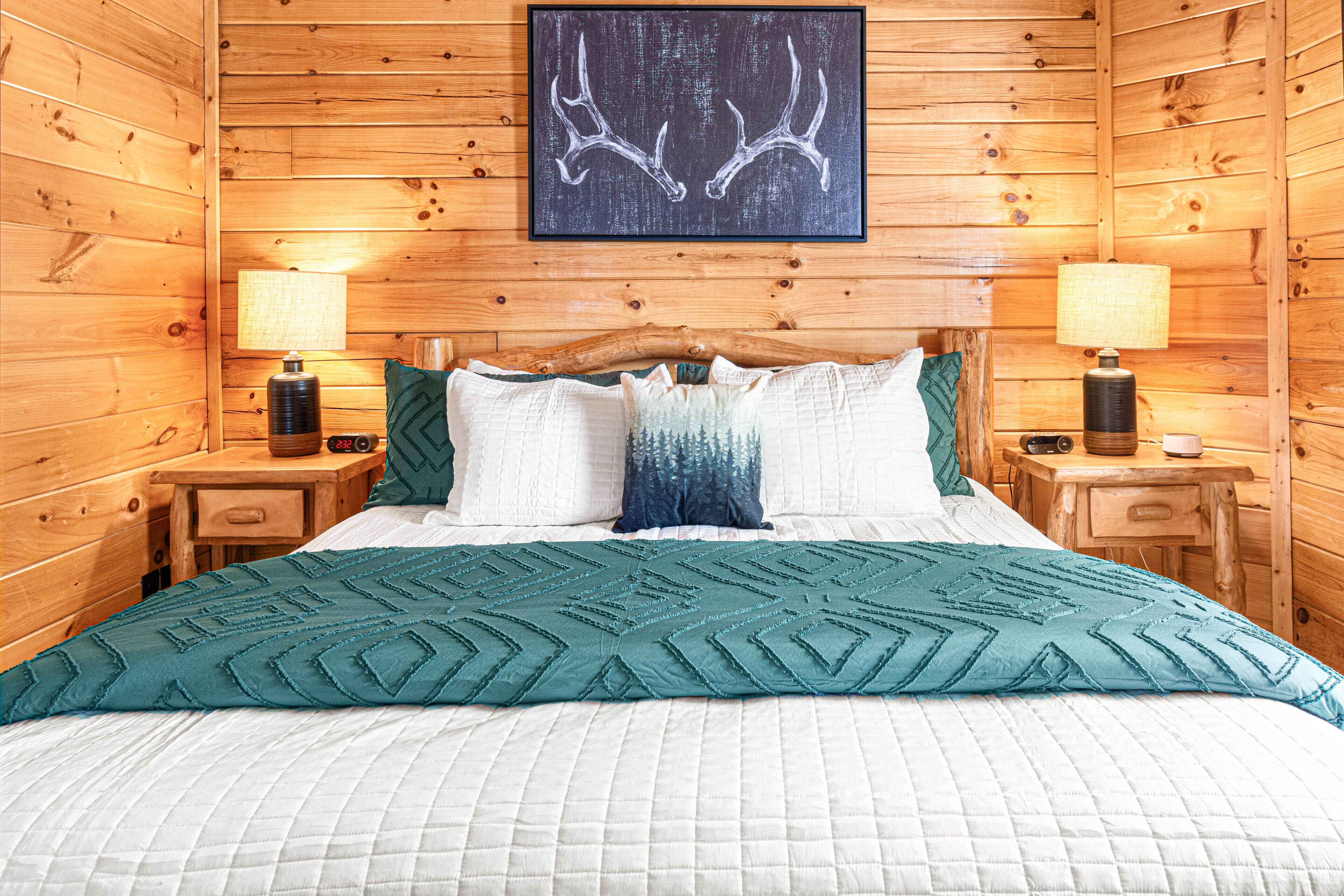Une chambre à coucher de style cabane en bois, avec un lit, deux tables de chevet et une lampe fixée au mur.