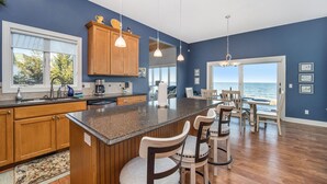A kitchen with wooden cabinets, a granite countertop, and a view of the ocean. - Exquisite Private Lake Front Family Home (Manistee)