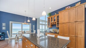 A kitchen with a granite countertop, wooden cabinets, and pendant lights. - Exquisite Private Lake Front Family Home (Manistee)
