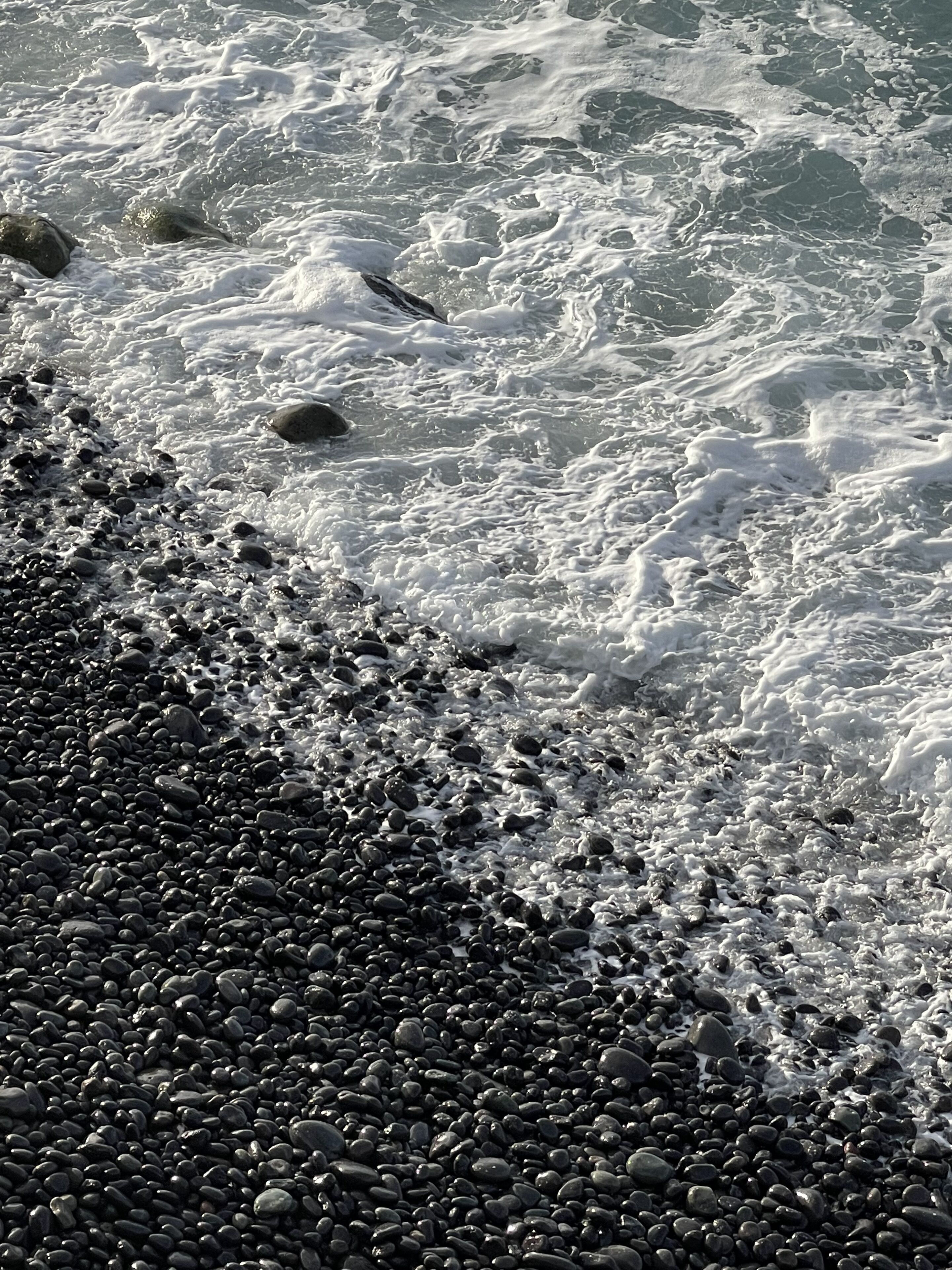 Une côte rocheuse où les vagues s’écrasent sur les galets.