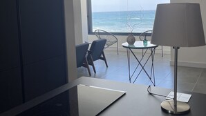 A modern room with a large window, a dining area with a table and chairs, and a kitchen with a stove. - Casa Lúa in front of the sea (Guía)