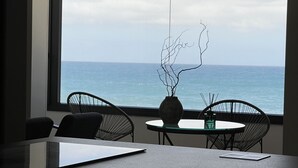 A modern room with a large window overlooking the sea, featuring a minimalist desk, two chairs, and a vase with branches. - Casa Lúa in front of the sea (Guía)