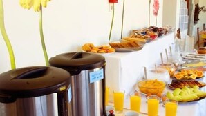 A buffet setup with various food items, a coffee station, and decorative flowers on the wall. - Kissamos Hotel (Kissamos)