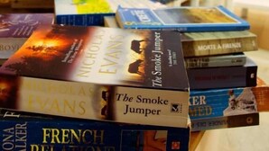 A stack of books on a table in a well-lit indoor area with seating and plants. - Kissamos Hotel (Kissamos)