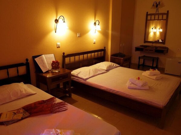 Habitación de hotel con dos camas, una mesita de noche y un espejo sobre la cama.