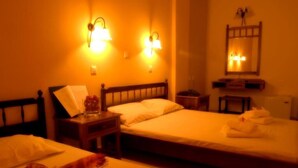 A hotel room with two beds, a nightstand, a mirror, and wall-mounted lights. - Kissamos Hotel (Kissamos)