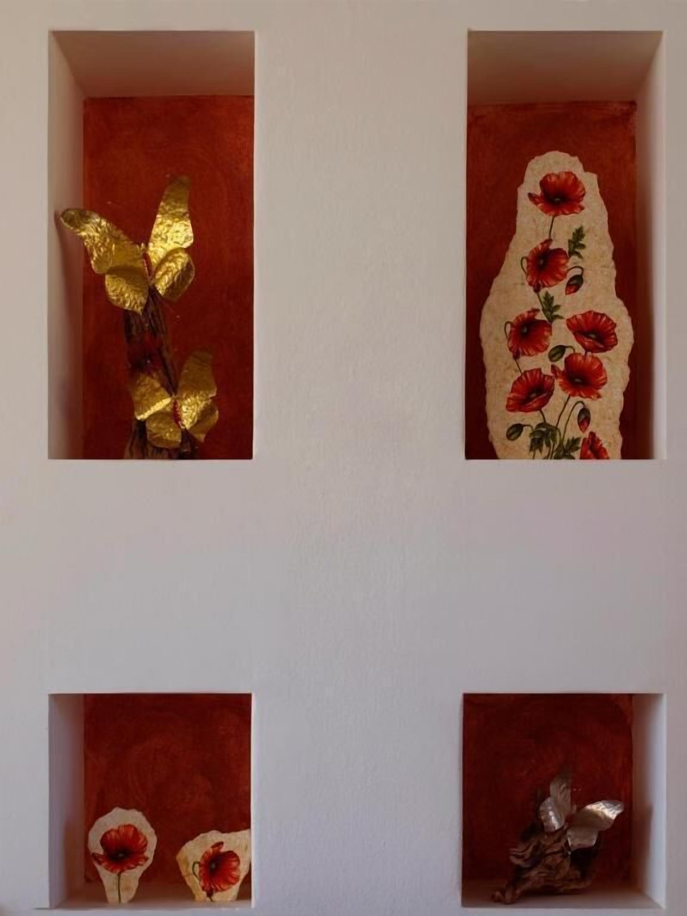 A wall with four square frames containing different decorative items.