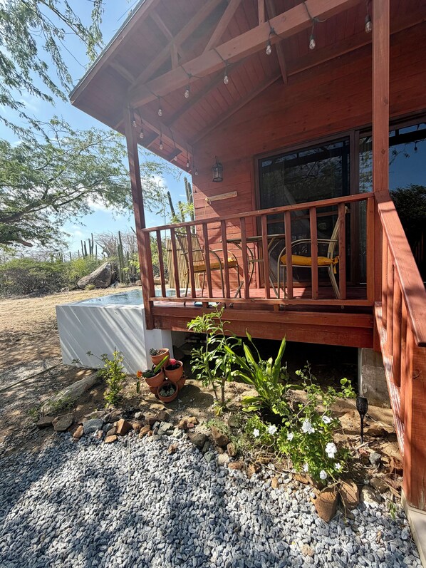 A wooden building with a balcony, gravel ground, and potted plants.