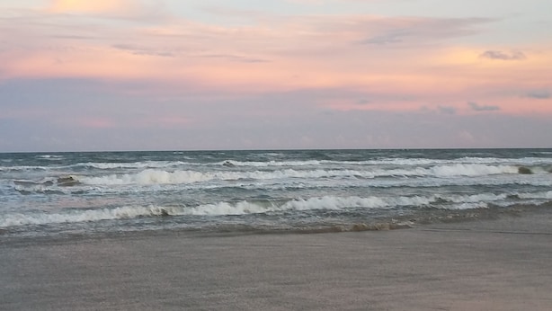 Una playa con olas y un cielo nublado.