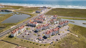 Vista aérea de un hotel costero con varias construcciones, estacionamientos y un puerto deportivo.