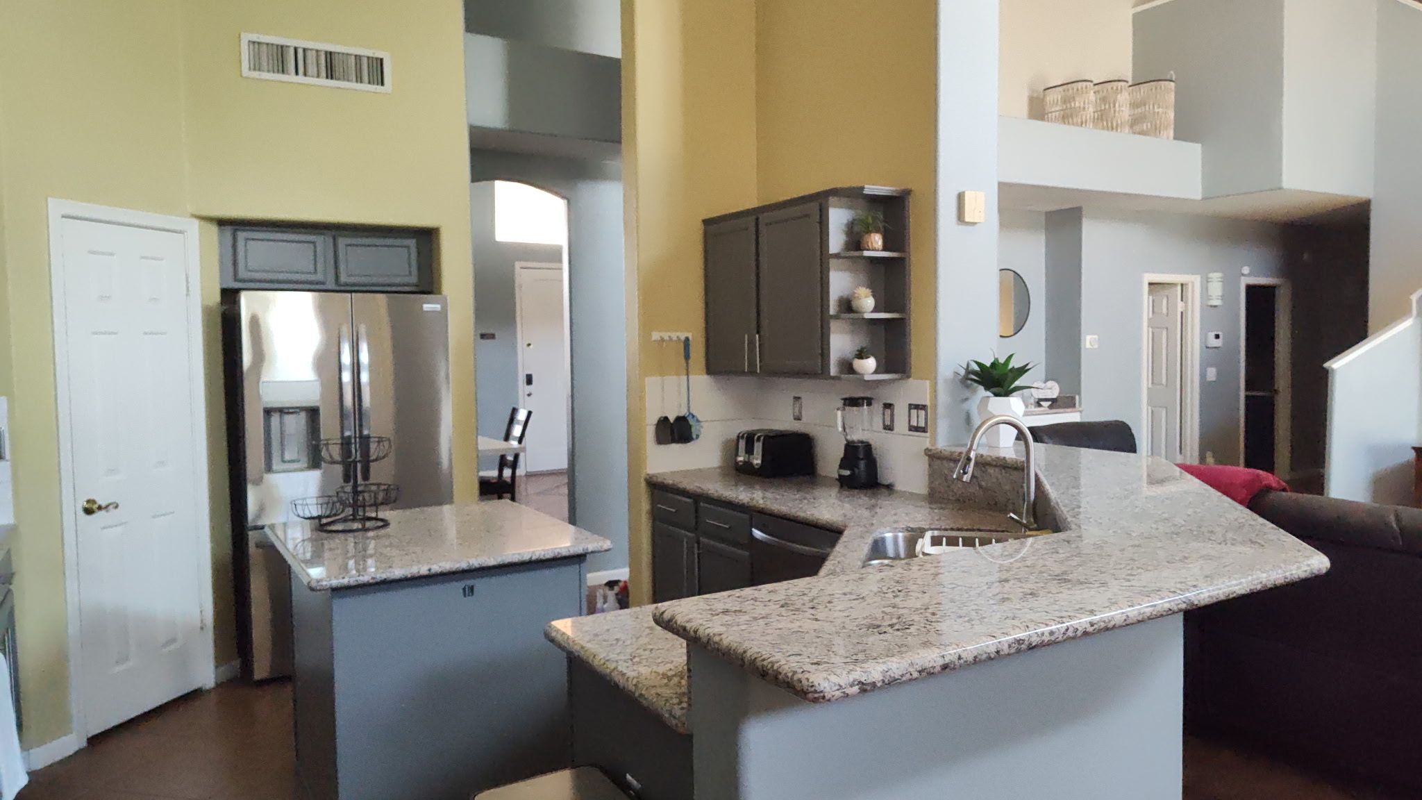 A compact kitchen with a central island, built-in appliances, and a dining area with a chair.