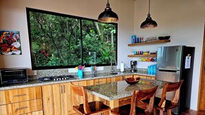 Une cuisine moderne dotée d’une grande fenêtre, de meubles en bois, d’un plan de travail en granit et d’une cuisinière encastrée.