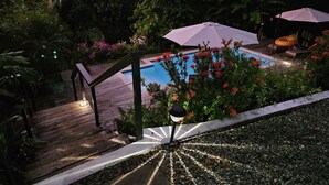 Un espace piscine doté d’une terrasse en bois, d’un chemin blanc et d’une bordure en pierre.