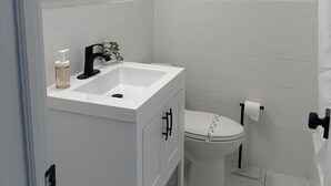 Une salle de bain avec un lavabo blanc, un miroir et des toilettes.