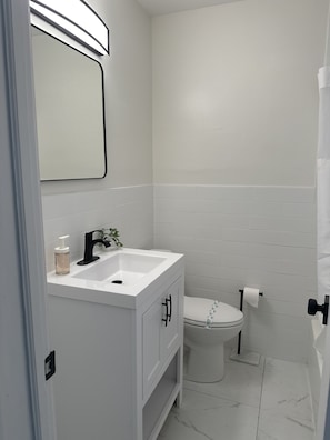 A bathroom with a white sink, mirror, and toilet.