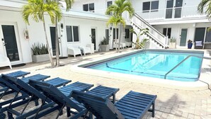 A swimming pool with lounge chairs and a staircase leading to a balcony. - Sapphire by the Sea Unit 5 King Studio King Bed, walk to the beach (Fort Lauderdale)
