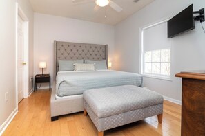 A bedroom with a bed, nightstands, a TV, and a window.
