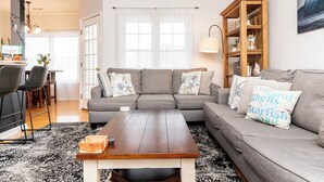 A living room with a grey sofa, a wooden coffee table, and a bookshelf. -  Cozy Creekwood Getaway on the Highway (Rehoboth Beach)