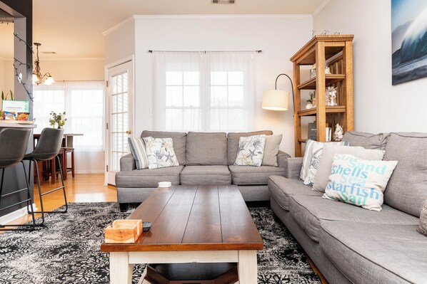 A living room with a grey sofa, a wooden coffee table, and a bookshelf.