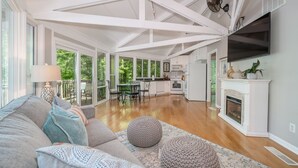 A spacious living area with a high ceiling, a fireplace, and a kitchen in the background. - Terrific home for a getaway! (Hot Springs)