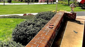 A brick wall with a flag, a green lawn, and a tree with pink blossoms. - Nearly 6000 sq ft of luxury living only 3 mi from PSU stadium (State College)