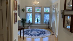 A hallway with a chandelier, a large patterned rug, and a Christmas wreath on the windows. - Nearly 6000 sq ft of luxury living only 3 mi from PSU stadium (State College)