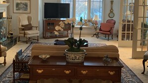 A spacious living room with a large window, a television, a sofa, a coffee table, and a fireplace. - Nearly 6000 sq ft of luxury living only 3 mi from PSU stadium (State College)