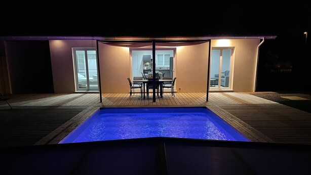 A swimming pool with a wooden deck and a glass-enclosed dining area. - House sleeps 4 with heated indoor pool ( Maison L'Estuaire) (Grayan-et-l'Hôpital)