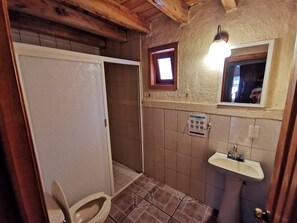 Et badeværelse med toilet, bruser og vask.