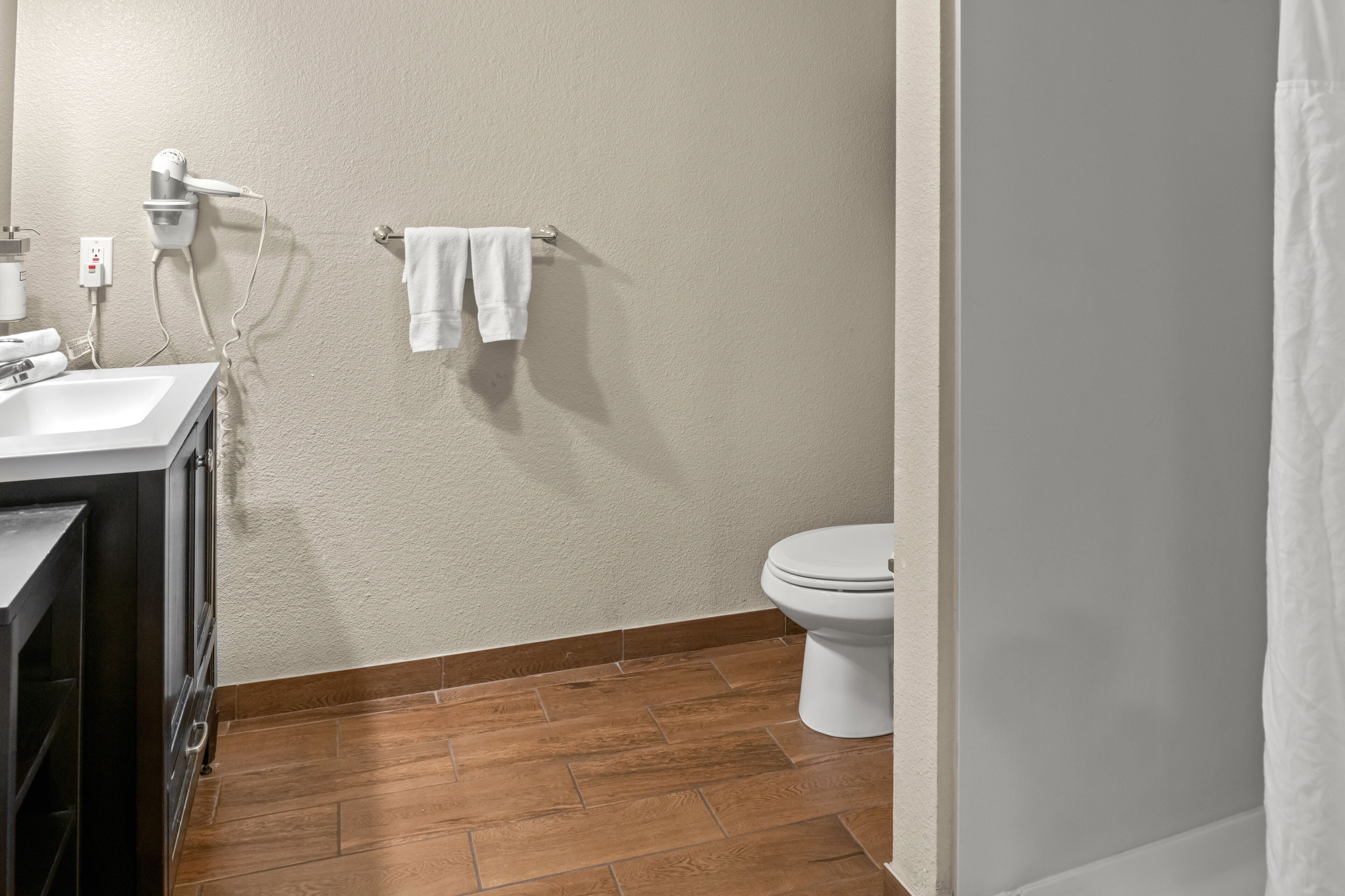 Een badkamer met een wastafel, spiegel, haardroger en handdoekhouder.