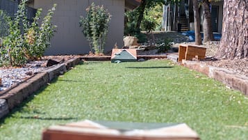 A well-maintained lawn with a wooden bench and a small shed in the background.