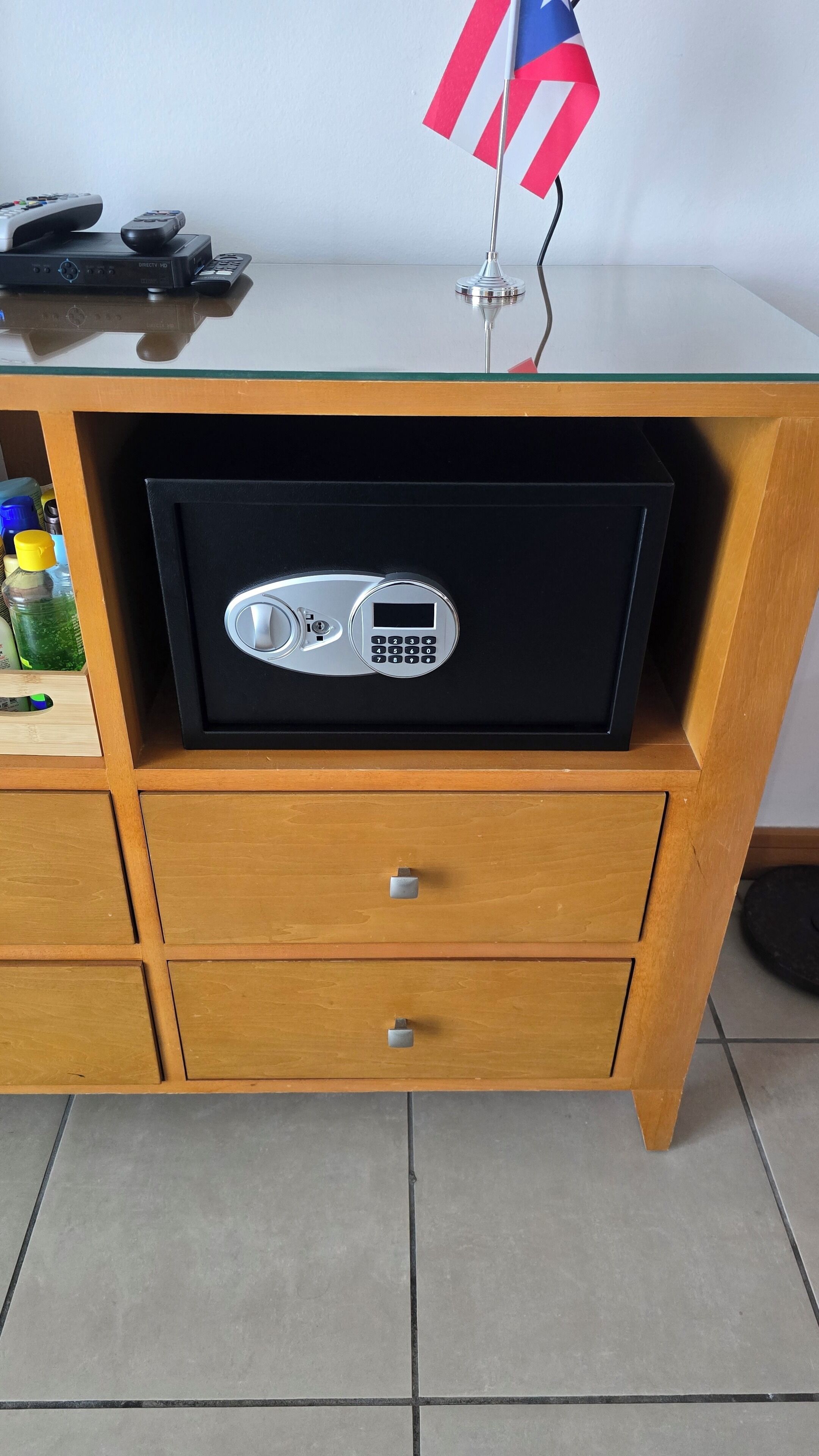 A wooden cabinet with a black safe, two drawers, and a flag on top.