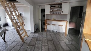Una cucina compatta con uno sgabello da bar in legno, un lampadario a sospensione e un'area lavanderia a vista.