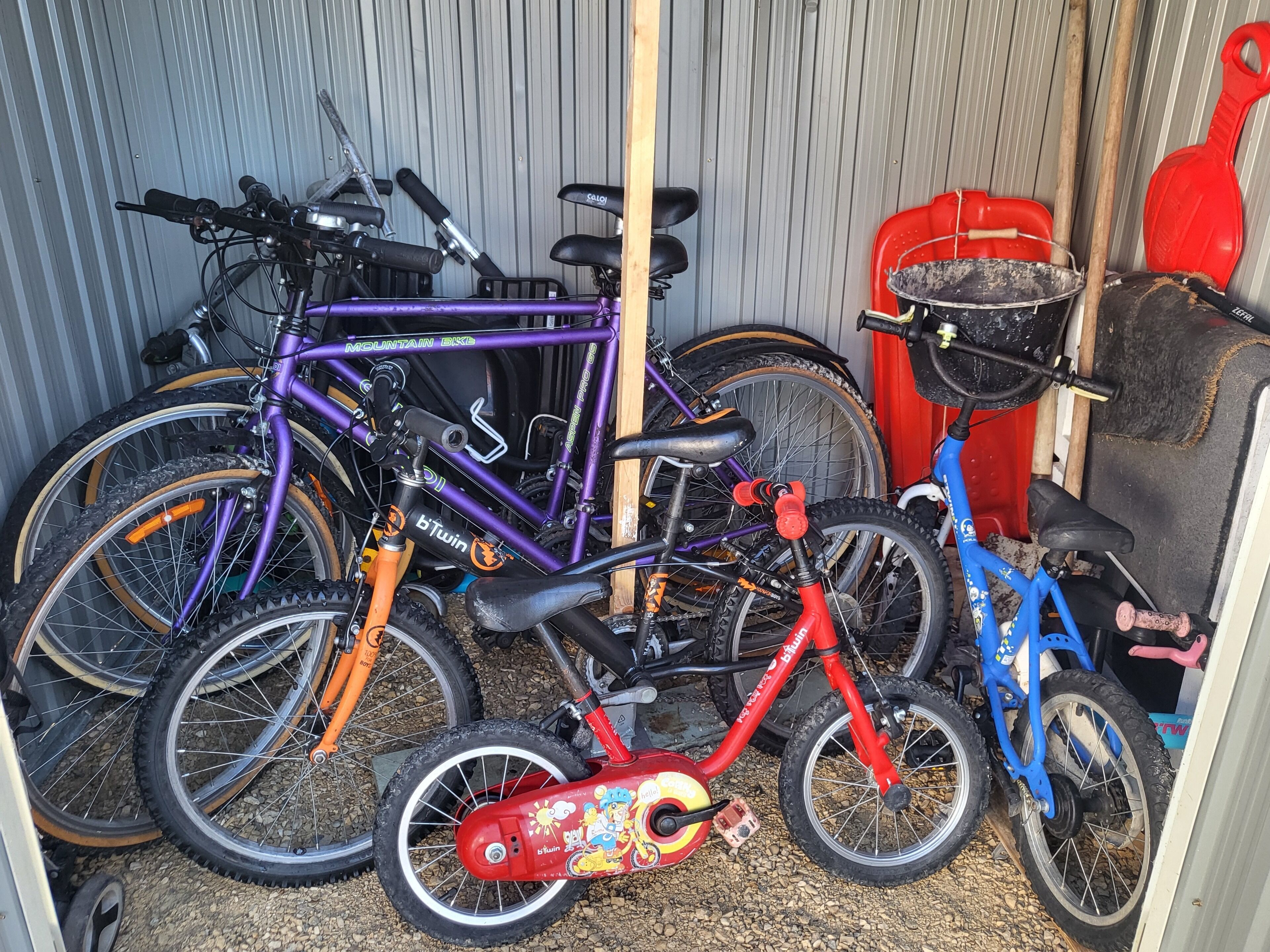 A storage area with bicycles and a red tricycle.
