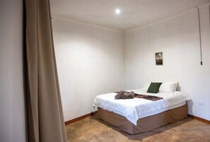 Ein Schlafzimmer mit einem Einzelbett, einem kleinen Wandbild und einem Vorhang auf der linken Seite.