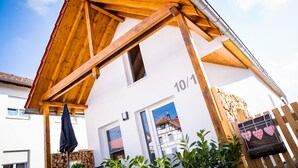 Ein Gebäude mit einem hölzernen Balkon, einer Tür mit der Beschriftung „10/1“ und einer Steinmauer.