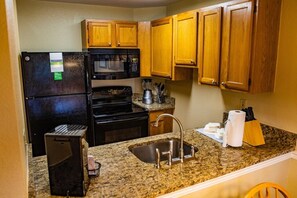 Fully equipped kitchen with a refrigerator, microwave, stove, and sink.