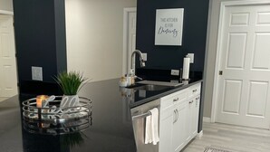 Eine moderne Küche mit schwarzem Arbeitsplatz, weißen Schränken und einem dekorativen Teppich.