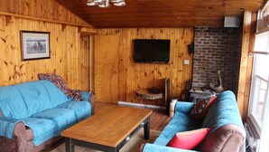 A cozy cabin interior with a blue sofa, a wooden coffee table, and a brick fireplace.