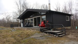 A small, modern building with a covered porch and red chairs.