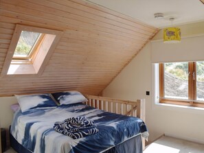 A bedroom with a sloped ceiling, a skylight, a bed with a blue and white patterned bedspread, a window with a view of the outdoors, and a yellow wall decoration. - 2 bedroom accommodation in Lendalfoot, near Girvan (Lendalfoot, near Girvan)
