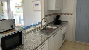 Una cocina con microondas integrado, un lavamanos y una ventana con vistas a un balcón.