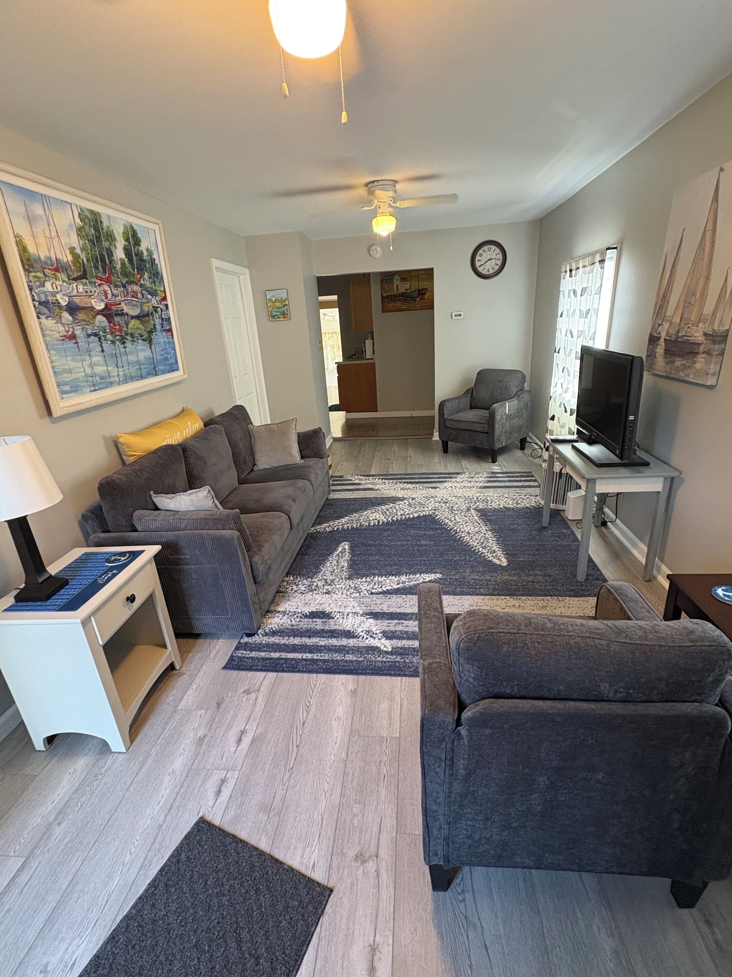 A living room with a sofa set, a television, and a painting on the wall.