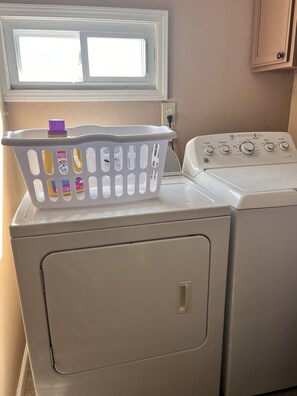 A front-loading washer and dryer with a laundry basket on top.